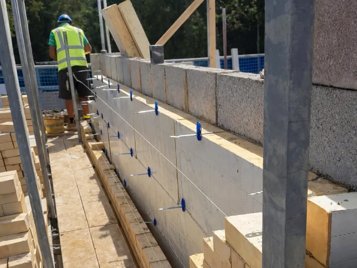 Construction worker building a brick wall outdoors.