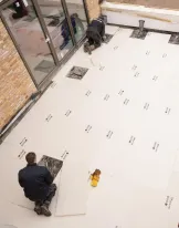 Workers laying tiles on a patio floor.