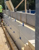 Construction worker building a brick wall outdoors.