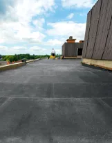 Flat rooftop with cloudy sky and distant person.