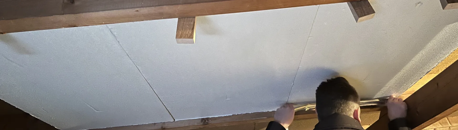 Man installing insulation panels in an attic.