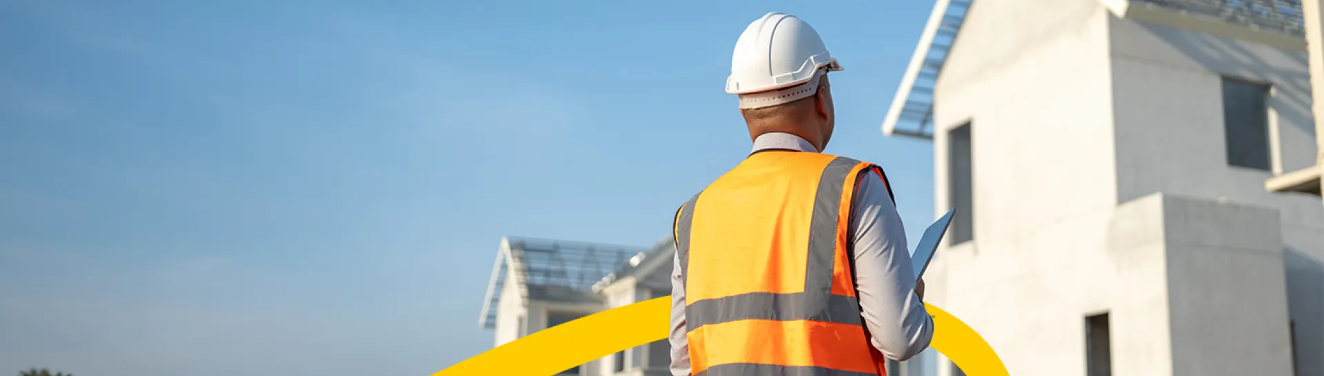 Worker in hard hat and vest inspecting a construction site.