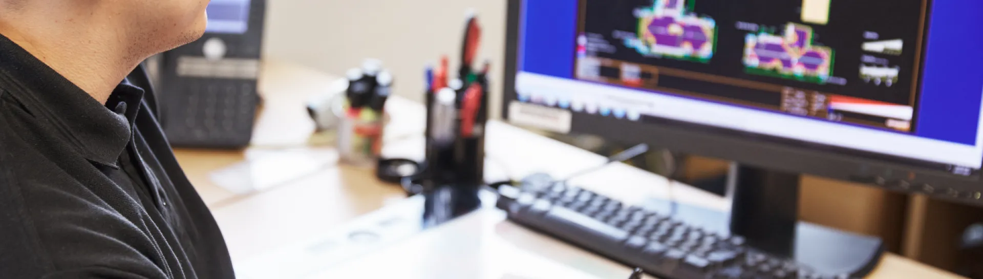 Man working on computer with technical drawings on screen.