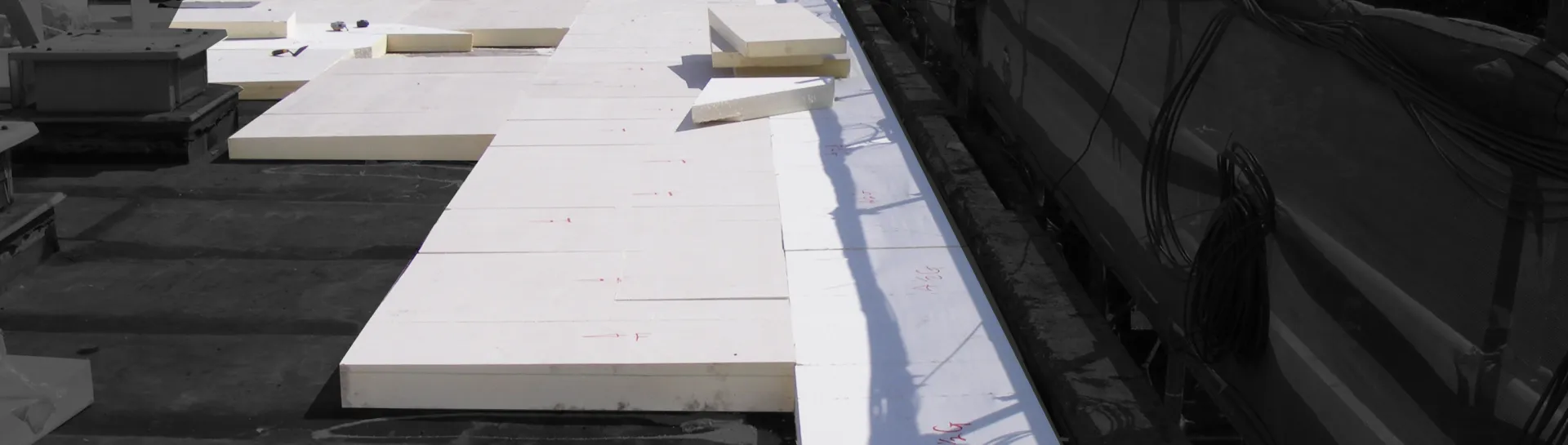 Flat roof with large white insulation panels laid out.