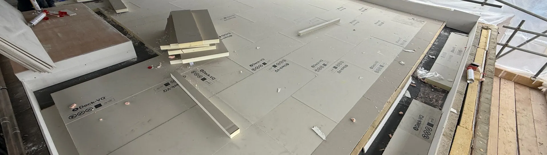 Flat roof construction with insulation and tools scattered.