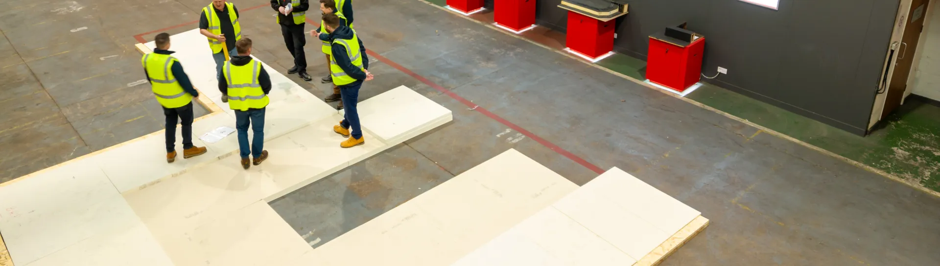 Workers in high-vis jackets standing in a warehouse, near signs marked "GRADIENT".