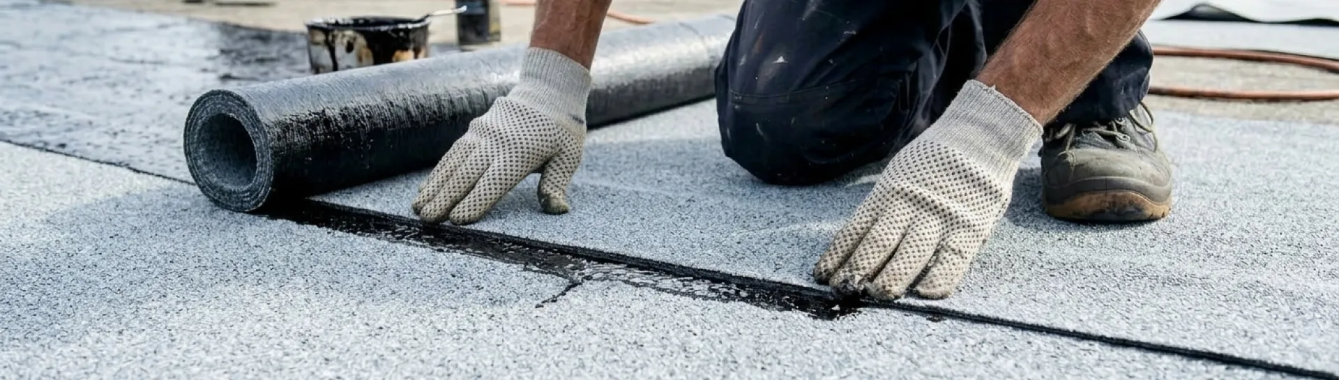 Roofer installing waterproof membrane on a flat roof.