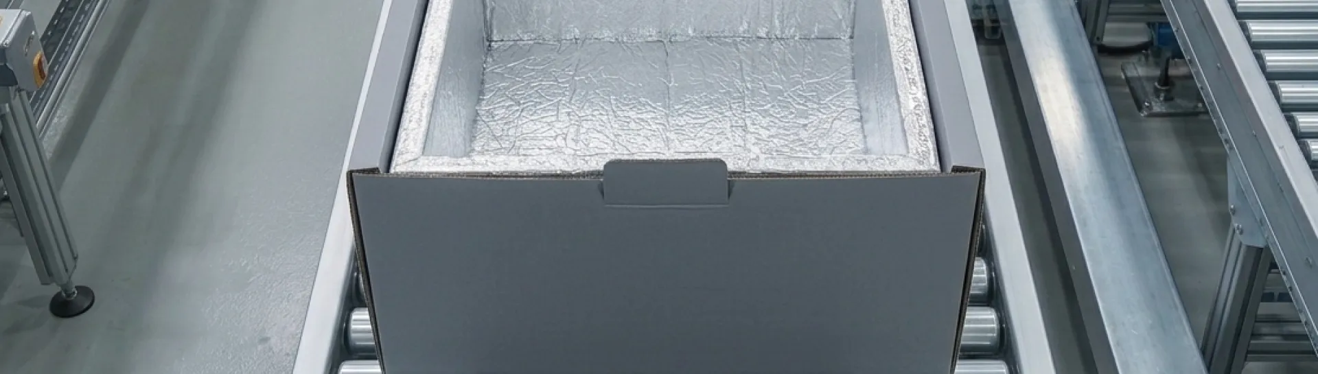 Cardboard box on conveyor belt in an industrial setting.