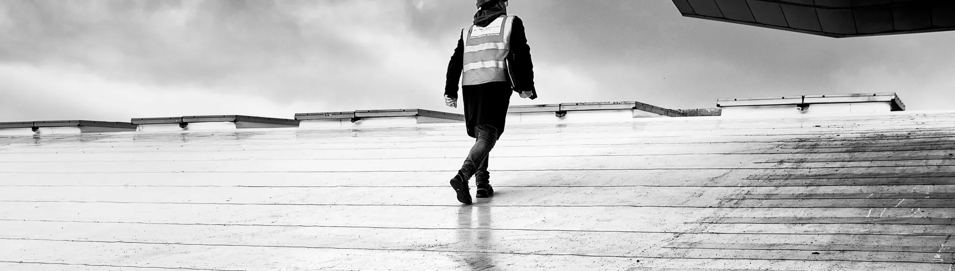 Walking person on a wet rooftop in black and white.