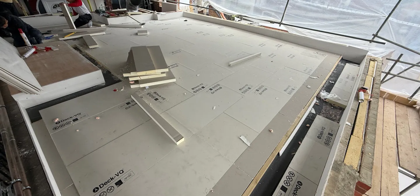 Flat roof construction with insulation and tools scattered.