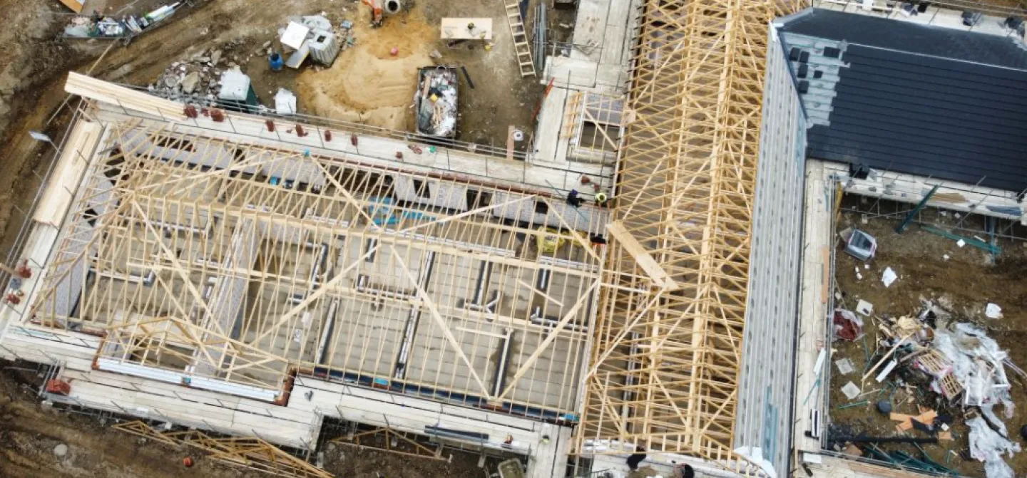 Aerial view of a building under construction with exposed wooden frames.