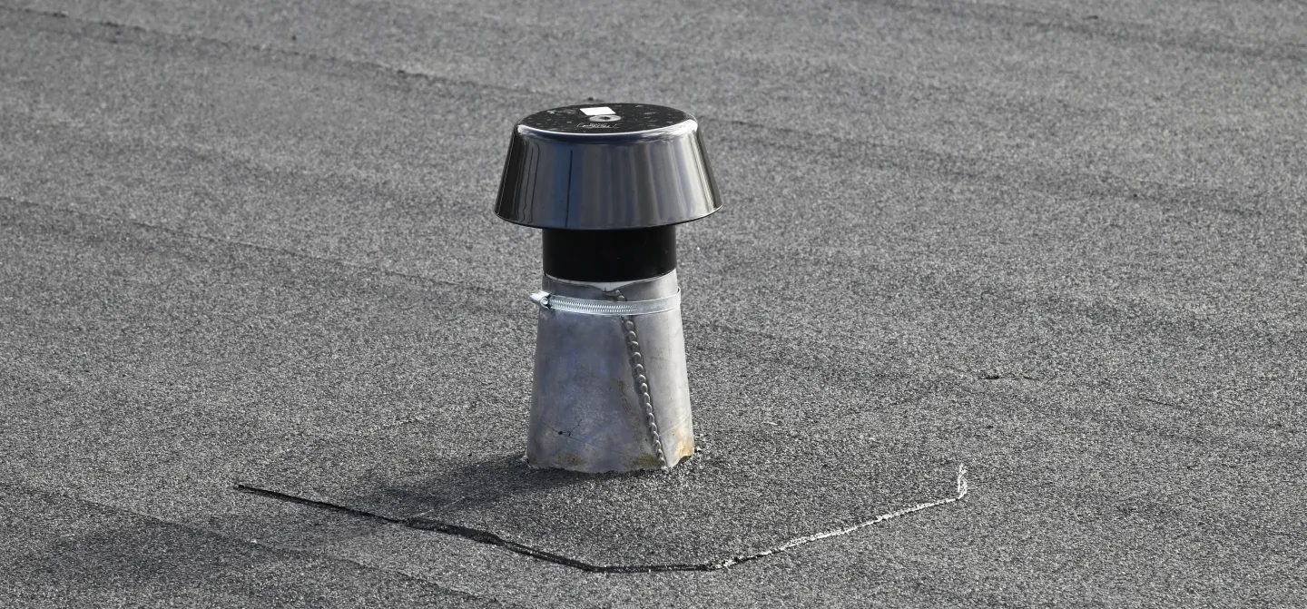 Vent pipe on a grey rooftop.