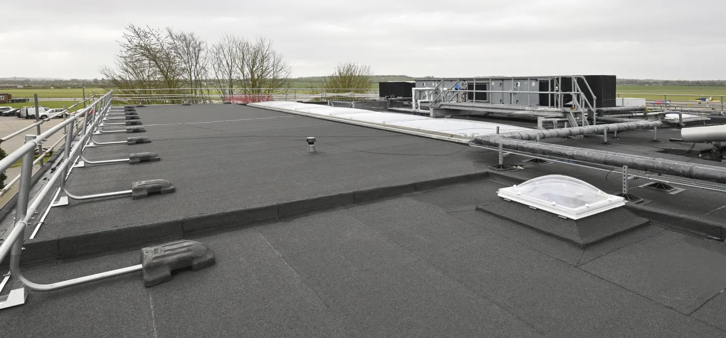 Flat rooftop with ventilation units under cloudy sky.