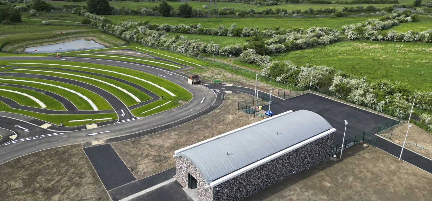 Aerial view of a rural landscape with a long, grey building and circular grassy patterns.