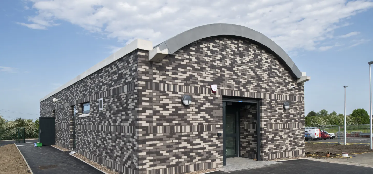Modern building with geometric brick pattern under a cloudy sky.