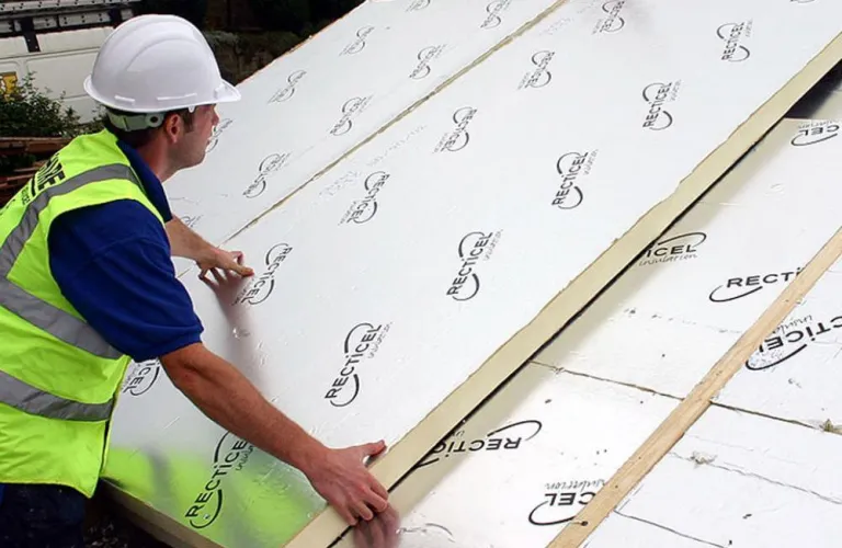 Construction worker installing insulated roof panels.
