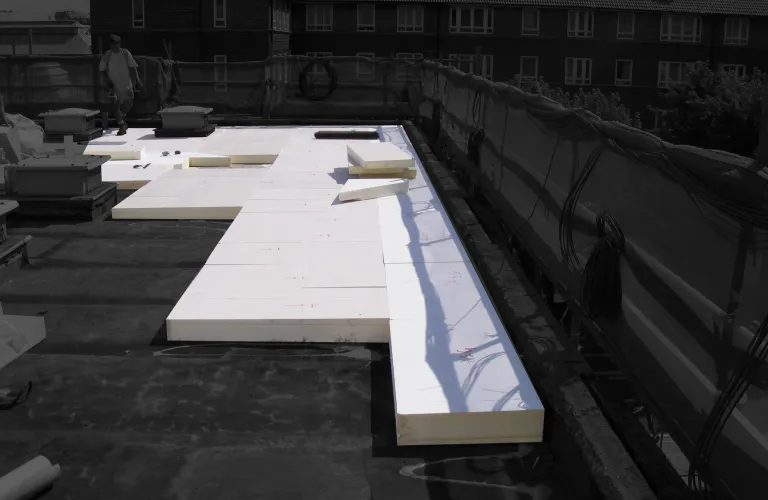 Flat roof with large white insulation panels laid out.
