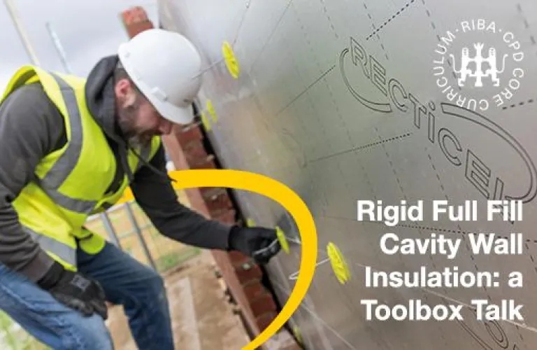 Worker in safety gear installing wall insulation.