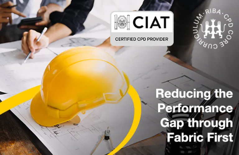 Yellow hard hat on desk with architectural plans.