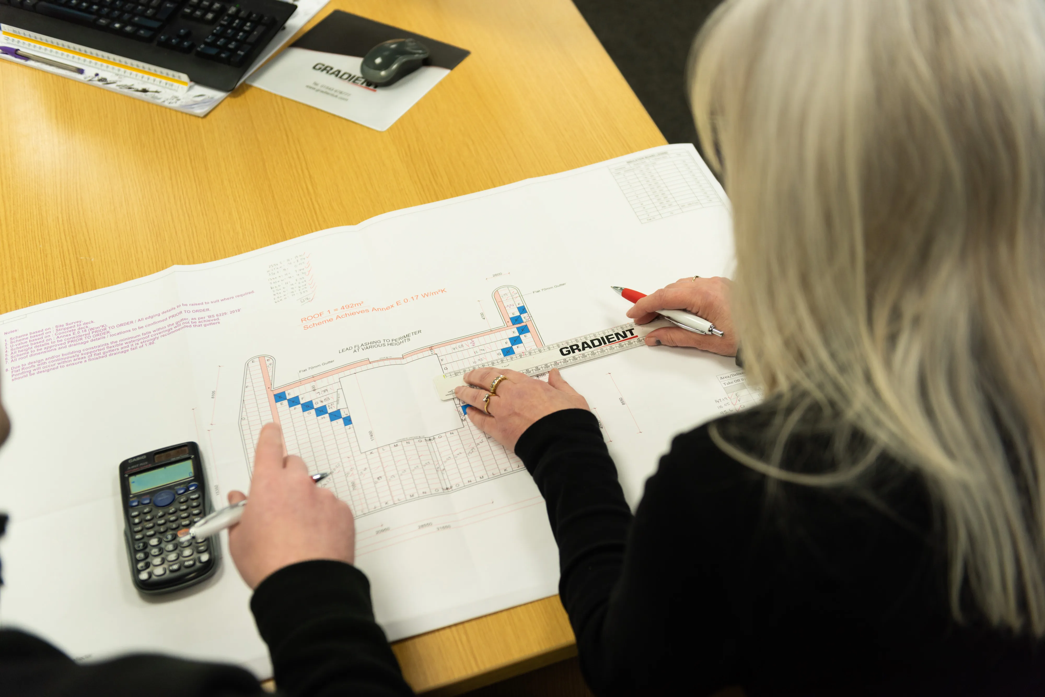 Two people reviewing architectural plans at a table.