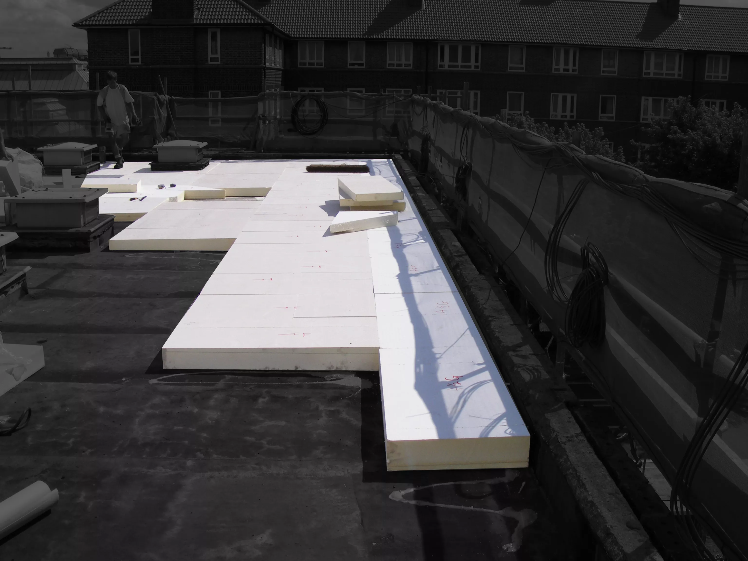 Flat roof with large white insulation panels laid out.