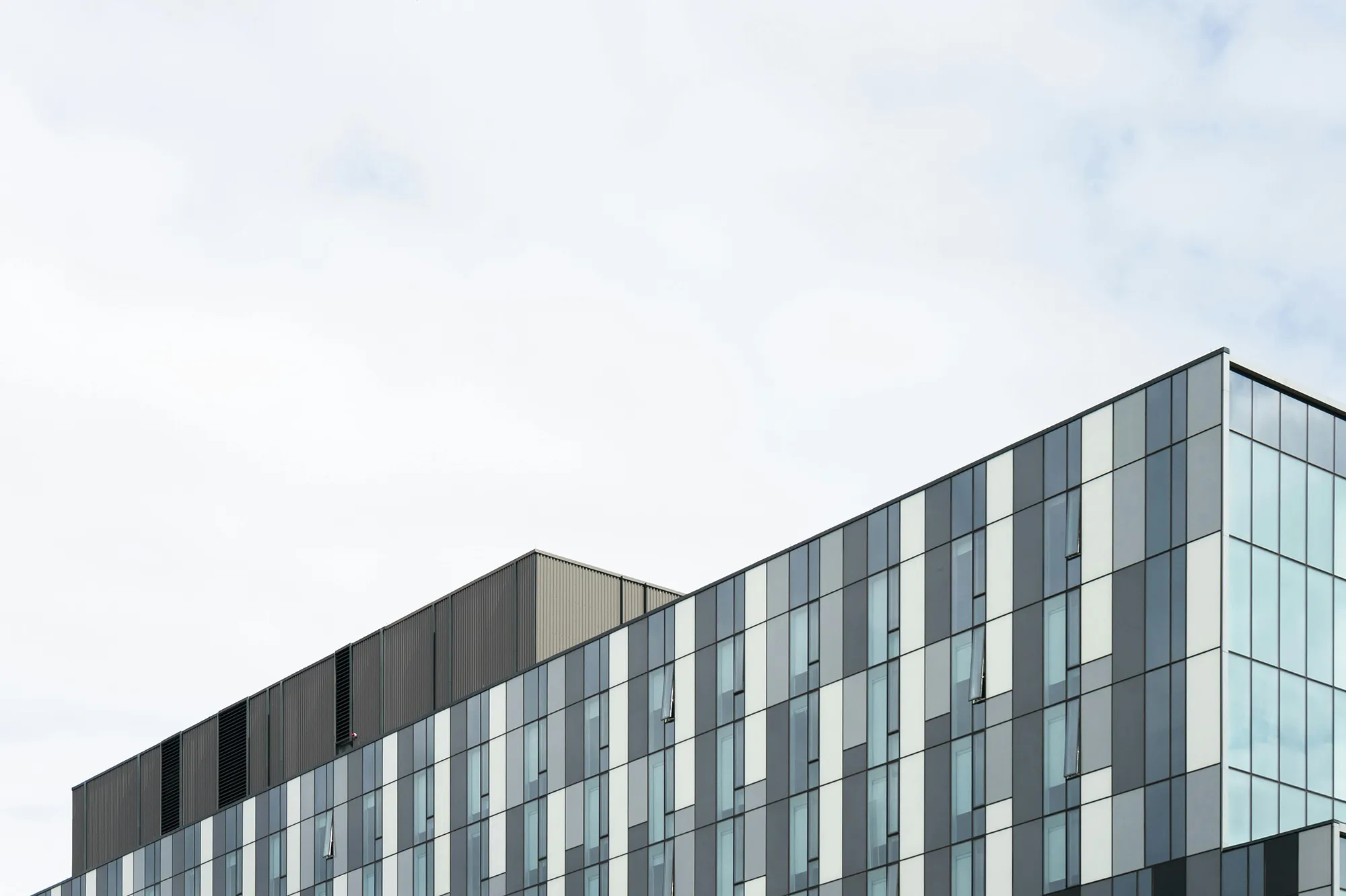 Modern glazen gebouw tegen bewolkte lucht.