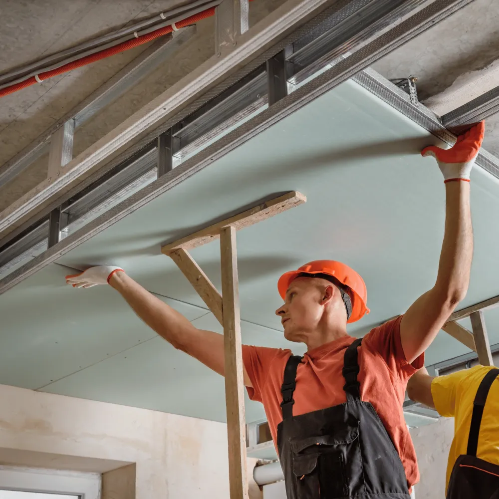 Construction worker installing a ceiling panel.