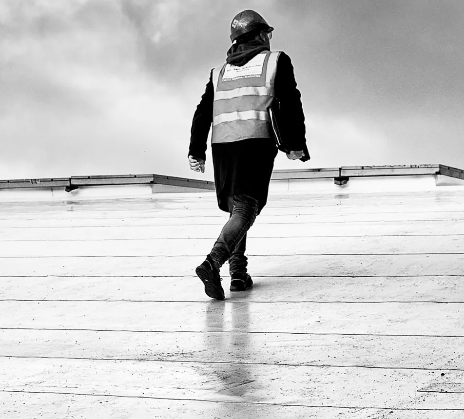 Walking person on a wet rooftop in black and white.