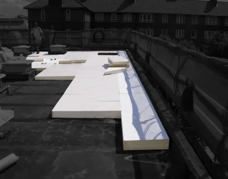 Flat roof with large white insulation panels laid out.