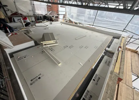 Flat roof construction with insulation and tools scattered.