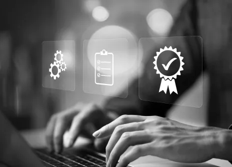 Typing on laptop with icons for settings, checklist, and certification.