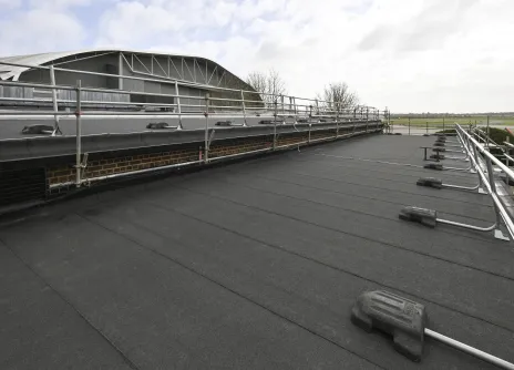 Flat rooftop with railings and cloudy sky.
